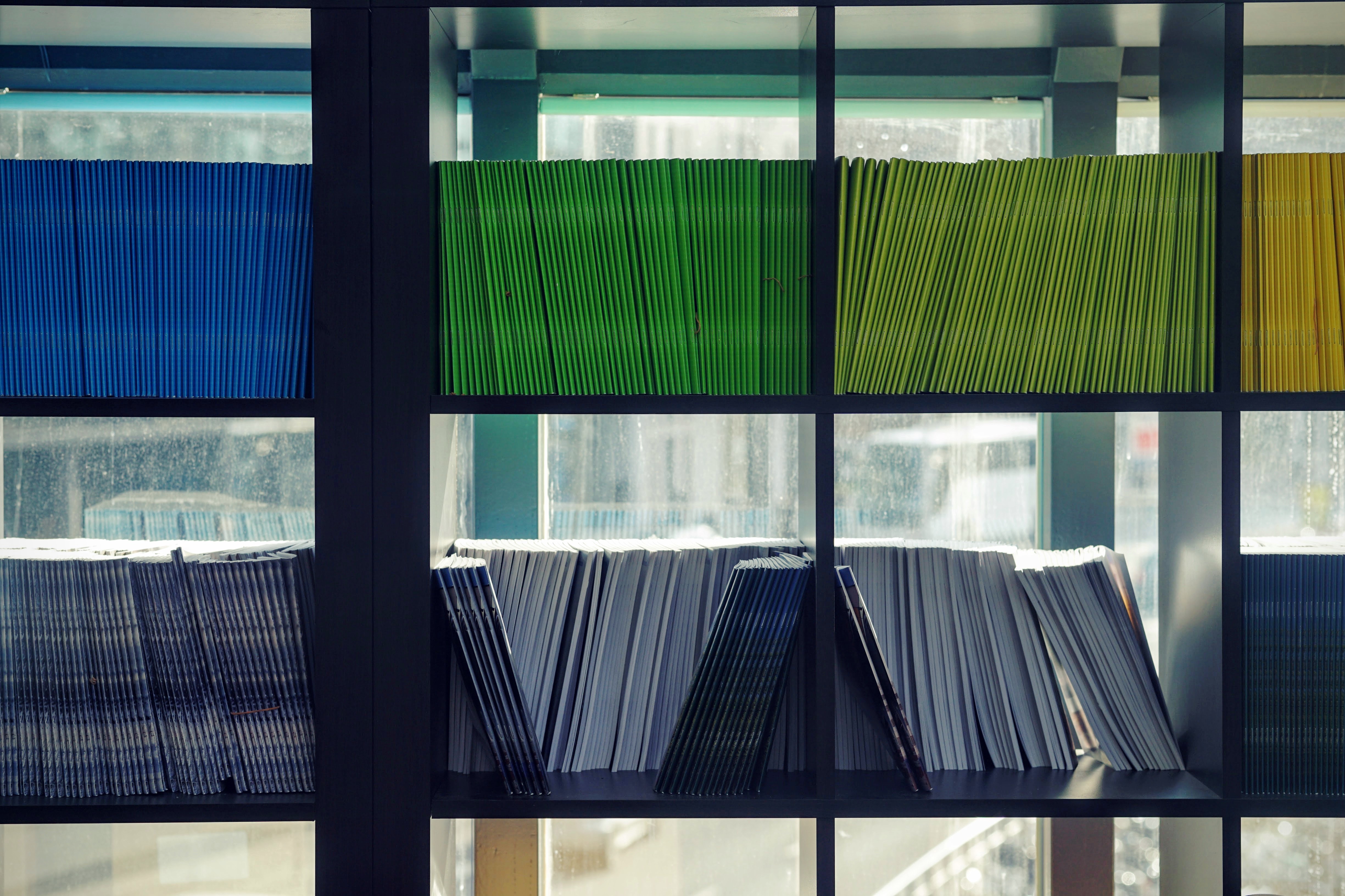A stack of various pamphlets sat on a shelf arranged by colour